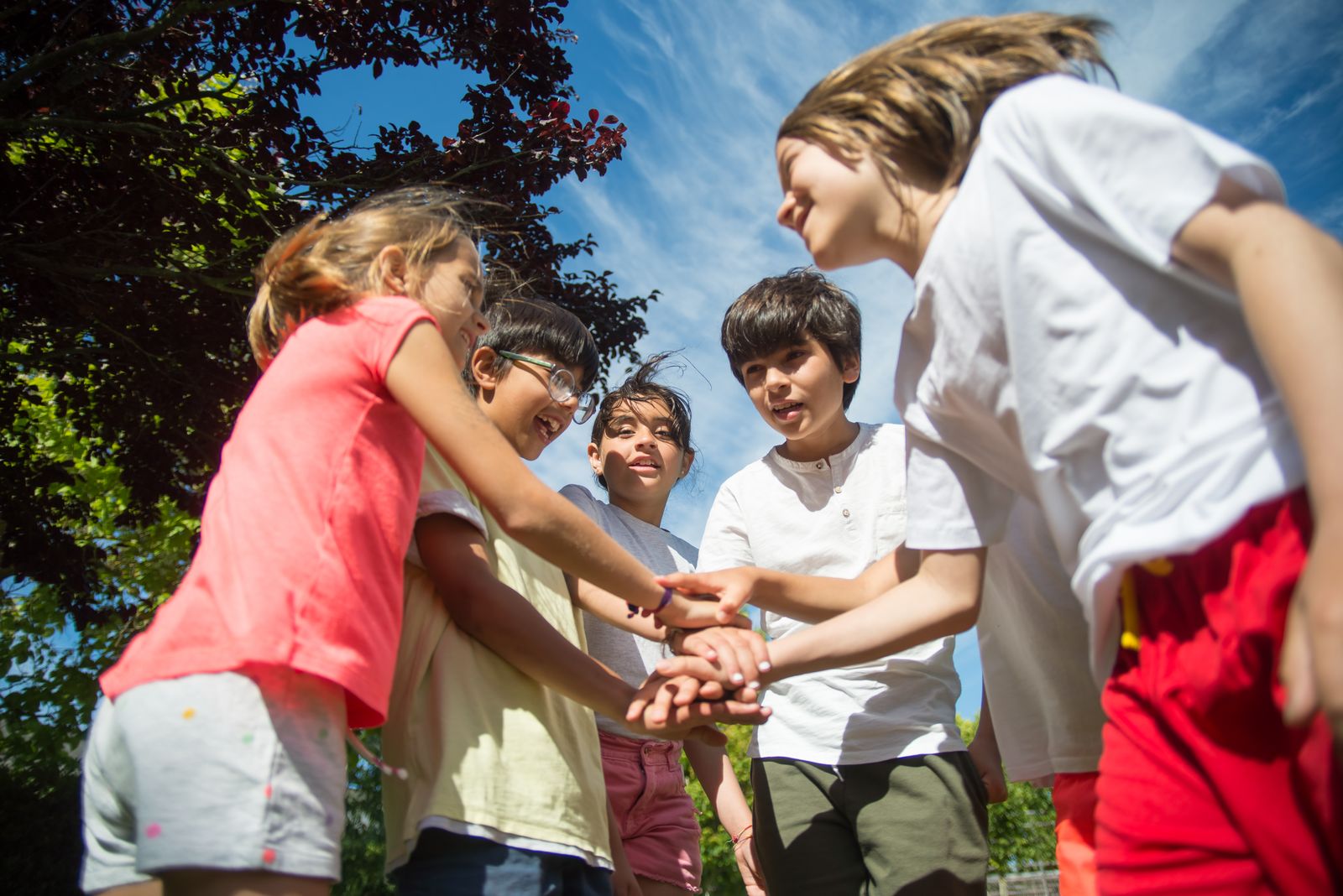 Happy children joining hands while playing together outdoors